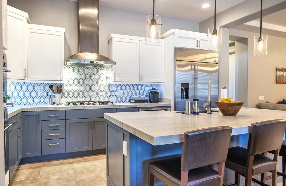 Slate blue island and base cabinets under a blue patterned backsplash