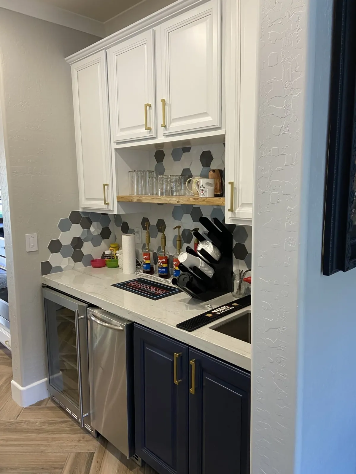 Butler's pantry with white uppers, navy base cabinets and a wine fridge