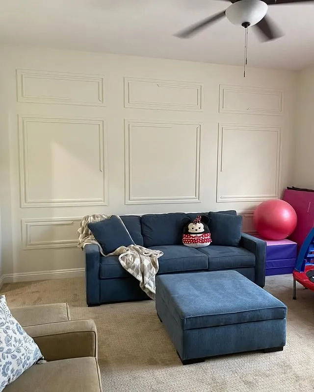 Playroom with panelled walls, a blue sofa and ottoman