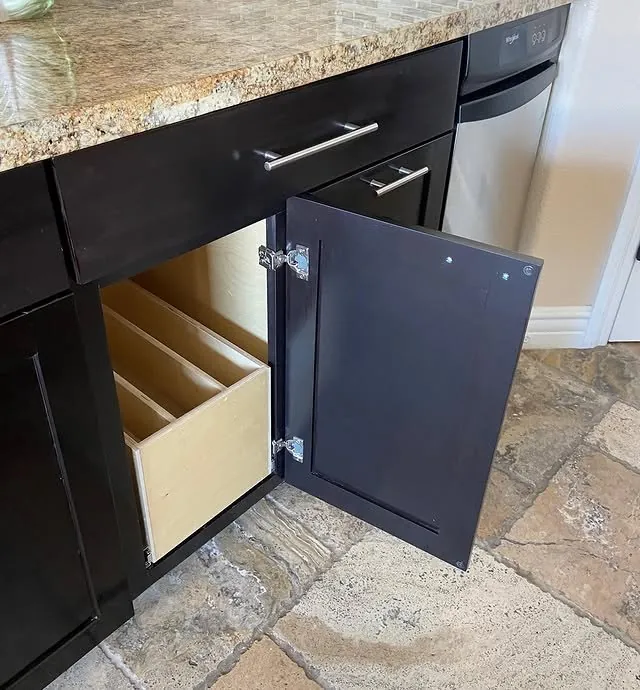 Base cabinet door open on vertical dividers for trays and cutting boards