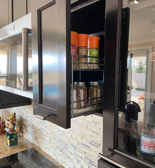 Narrow spice pull-out beside the range, stocked with jars
