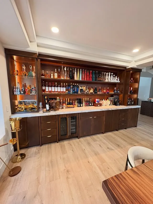 Wide view of the walnut bar with backlit shelves full of bottles
