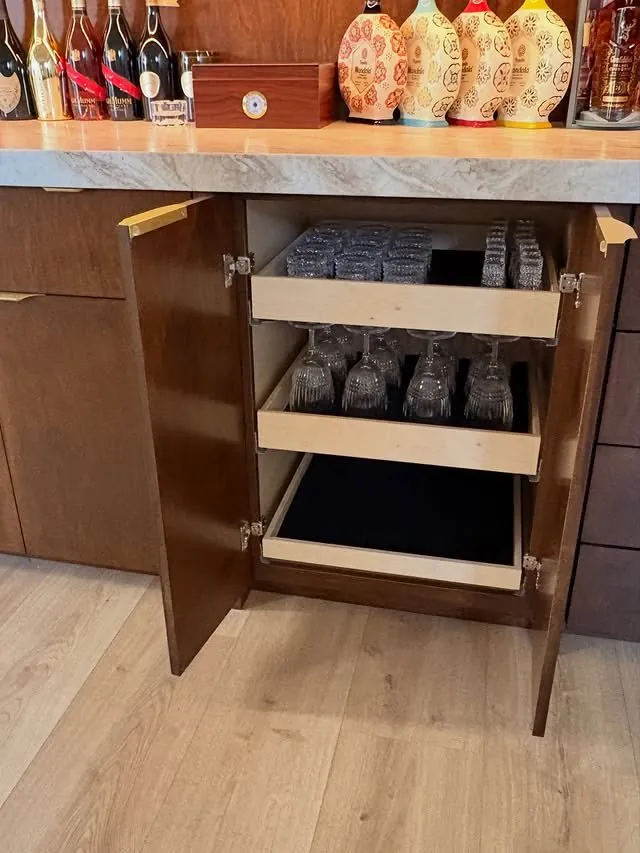 Base cabinet open on roll-out trays for bottles