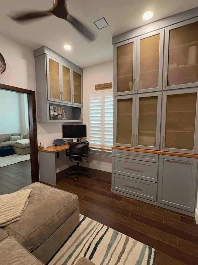 Office with an L-shaped cherry desk and a sofa