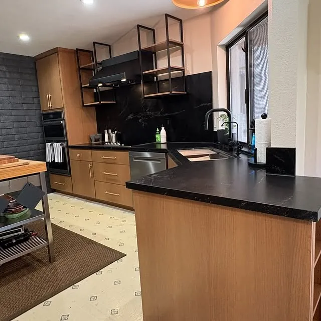 Mid-century kitchen with pecan slab cabinets, black granite and open steel shelving over the peninsula