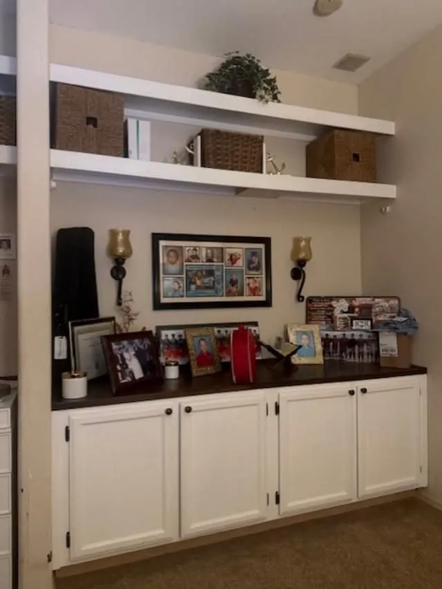 White base cabinets with open shelves and framed photos above