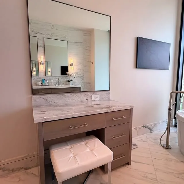 Walnut makeup vanity with a marble top, a tall mirror and a white tufted stool