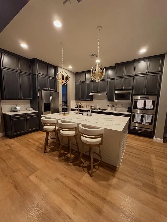 Kitchen with dark cabinets to the ceiling and a white island with three stools