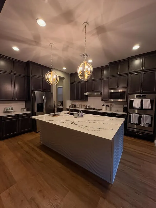 Kitchen with the island, pendants and dark tall cabinets