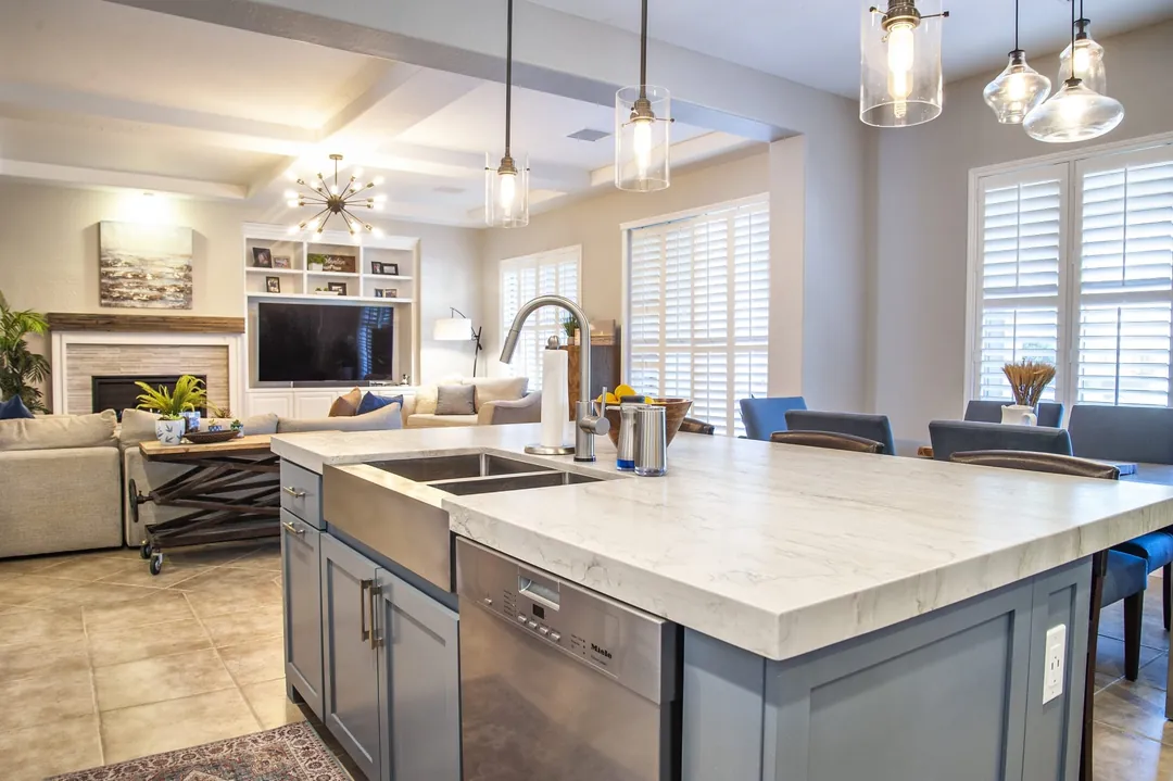 Kitchen island with a white quartz top and a stainless sink, open to the family room