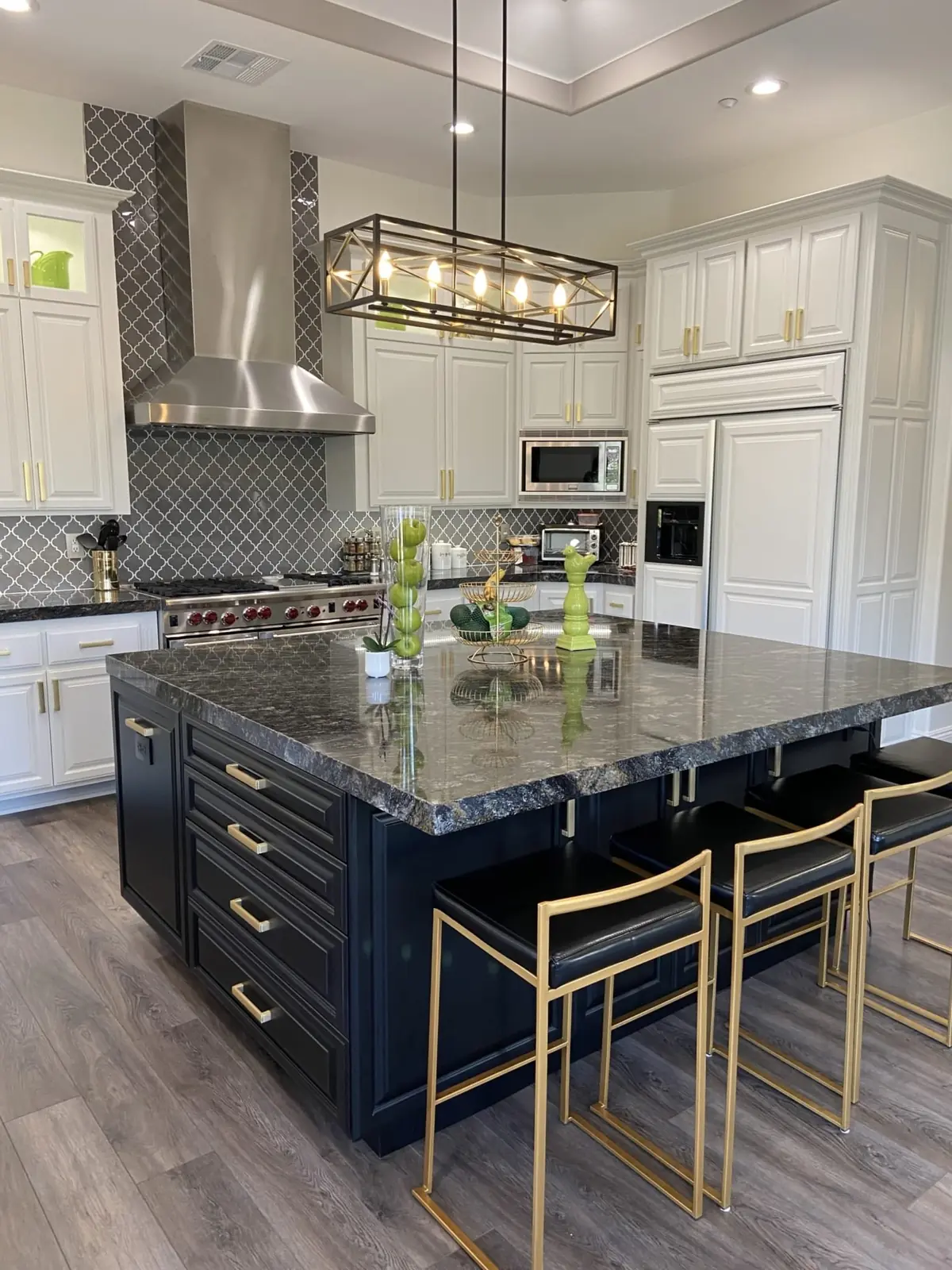 Navy island and white perimeter cabinets with a linear chandelier