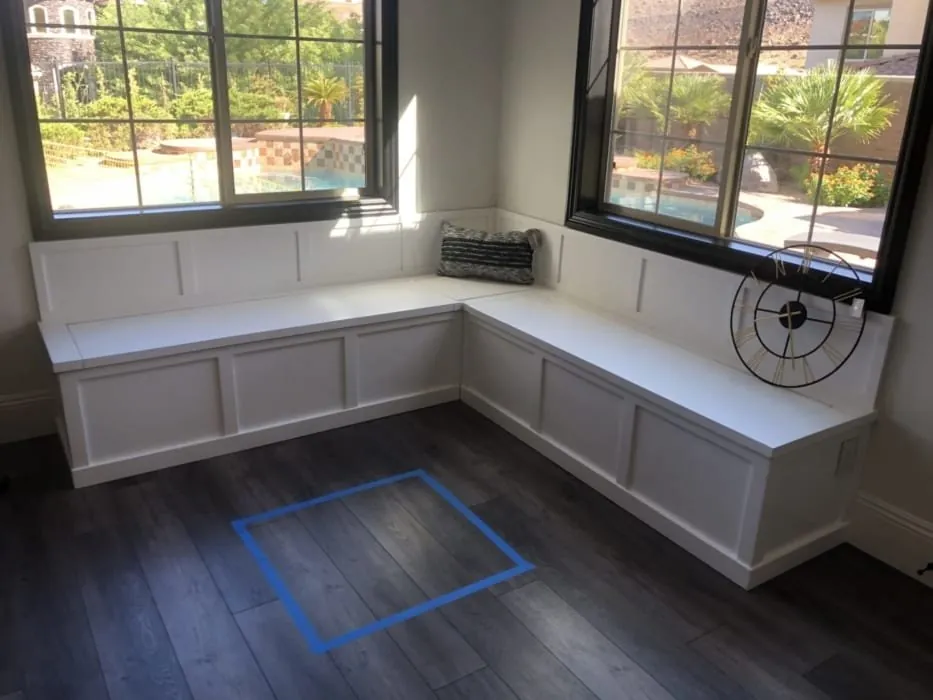 The white L-shaped banquette installed under the windows, with tape marking the table position
