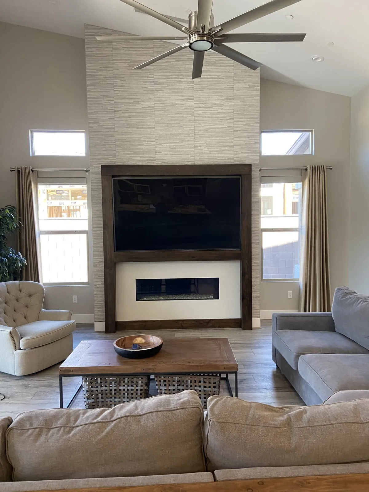 Full-height stacked-stone wall with a wood-framed TV over a linear fireplace
