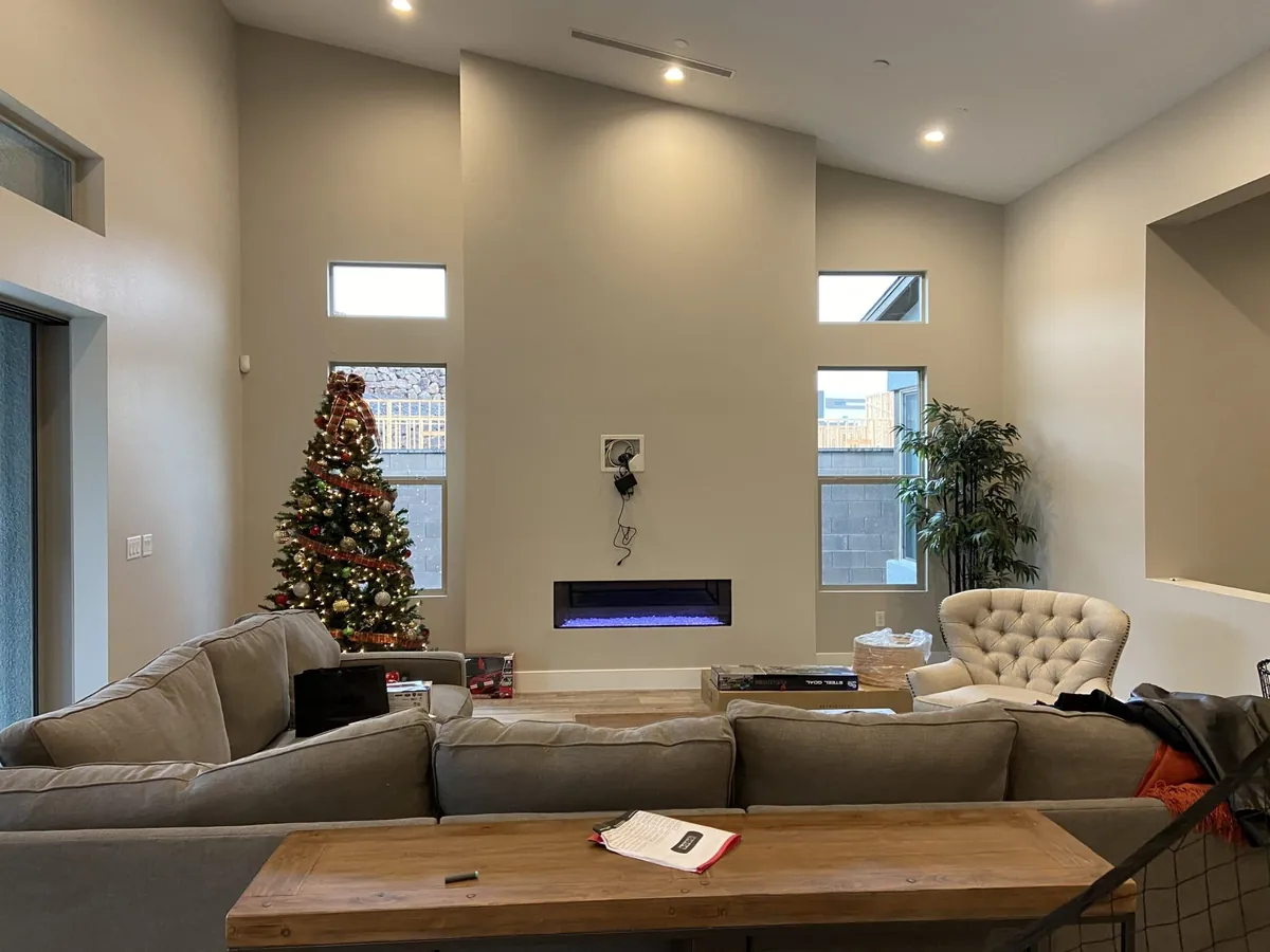 The living room before, with a small fireplace on a tall plain wall