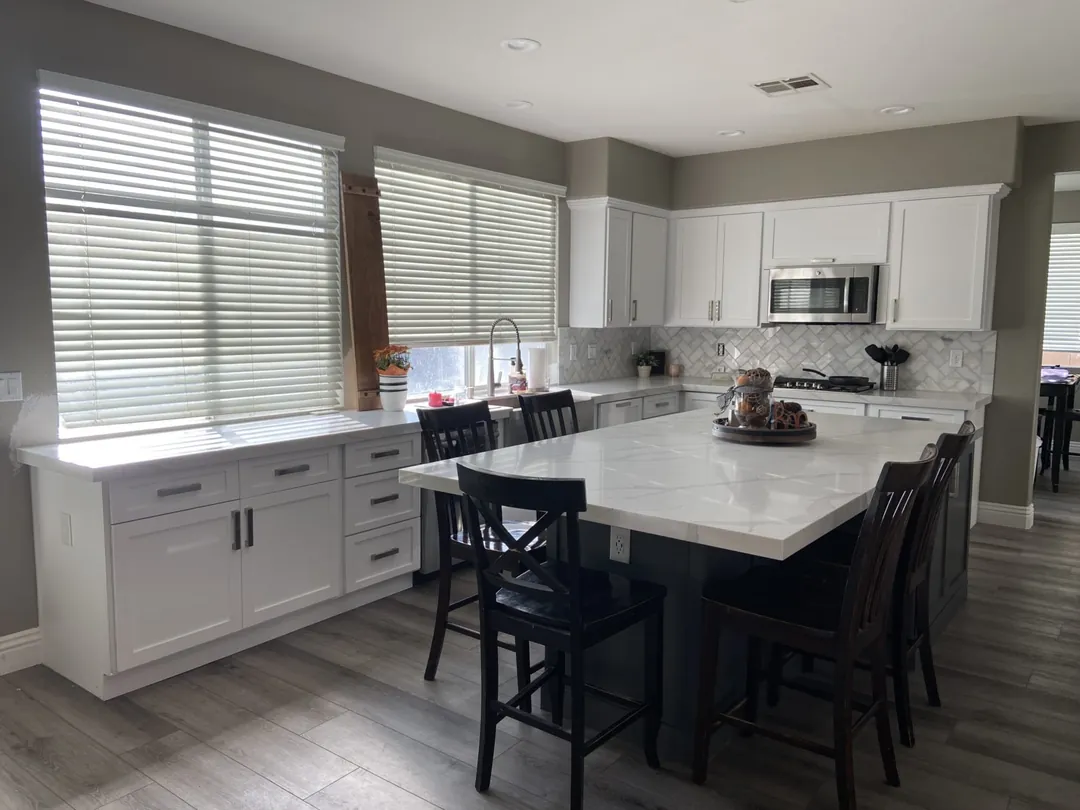 White shaker kitchen with a long dark grey island and black chairs