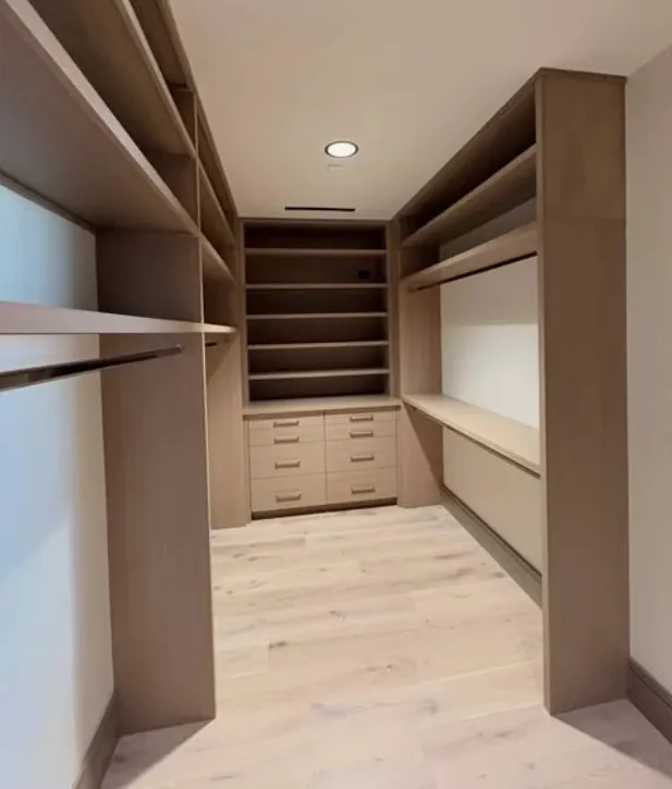 Walk-in closet with light wood shelving, hanging rods and drawers