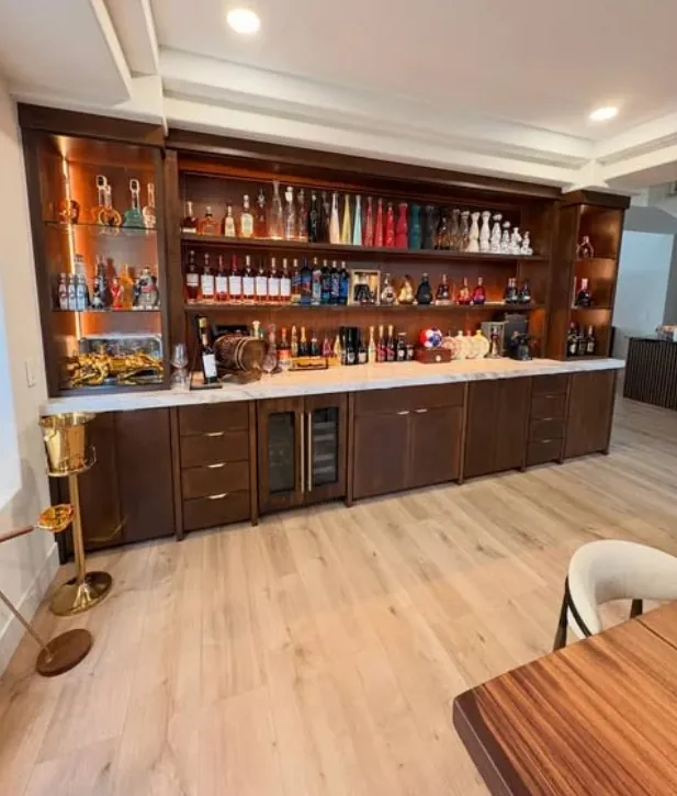 Walnut bar wall with lit bottle shelves above a long base cabinet