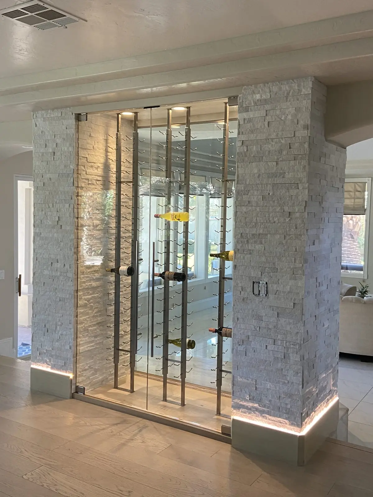 Glass-fronted wine display in a stone column, lit from the floor